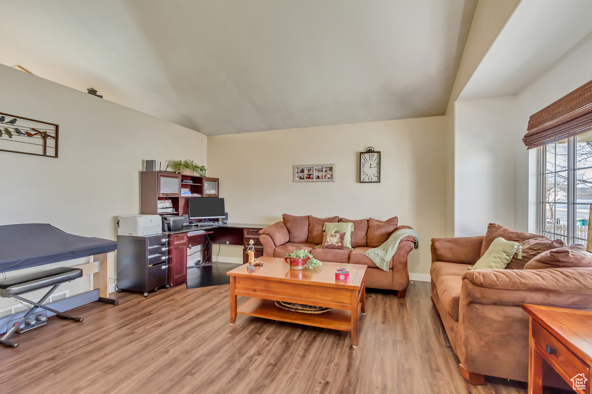 Living area with light wood-type flooring, baseboards, and vaulted ceiling