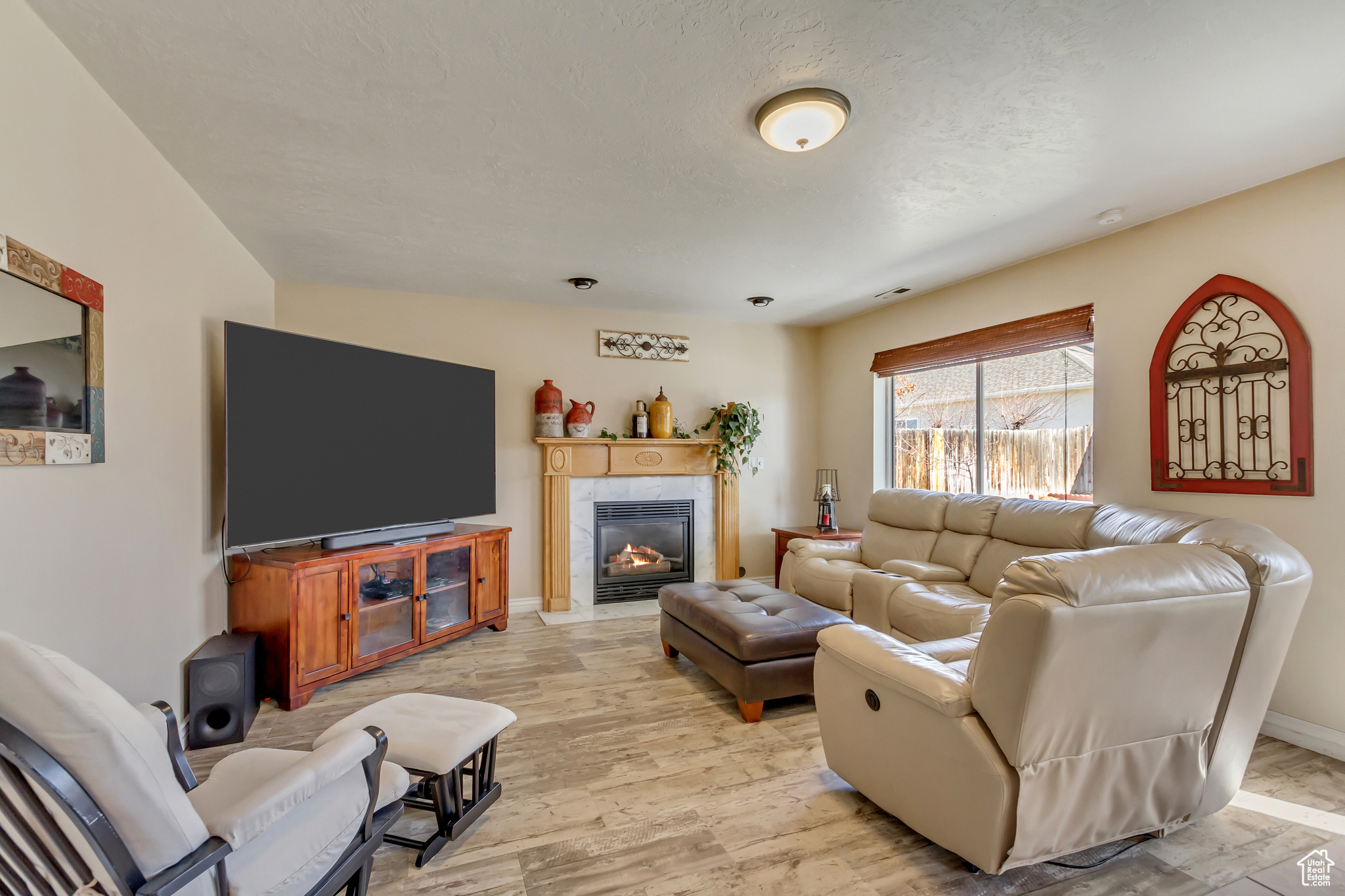 Living area with light wood-type flooring, baseboards, a textured ceiling, and a fireplace