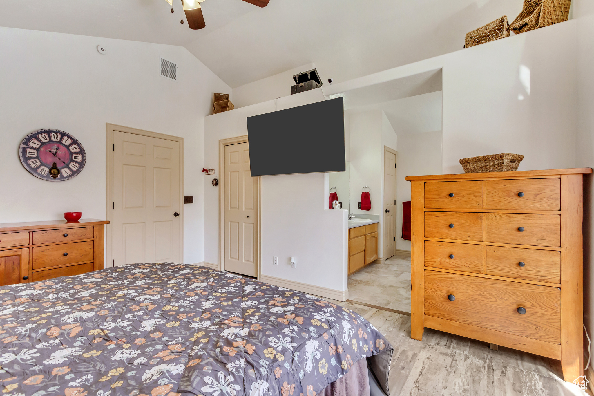 Bedroom featuring visible vents, ceiling fan, lofted ceiling, light wood-style flooring, and ensuite bathroom