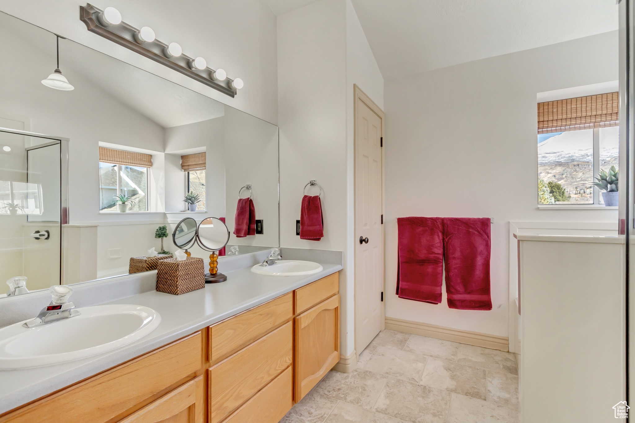 Full bathroom with double vanity, vaulted ceiling, a stall shower, and a sink