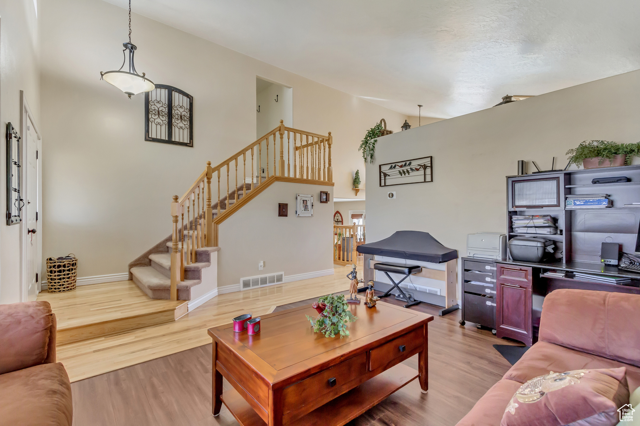 Living room featuring stairs, a high ceiling, light wood-style flooring, and visible vents