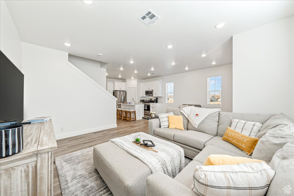 Living room with visible vents, recessed lighting, light wood-type flooring, and baseboards