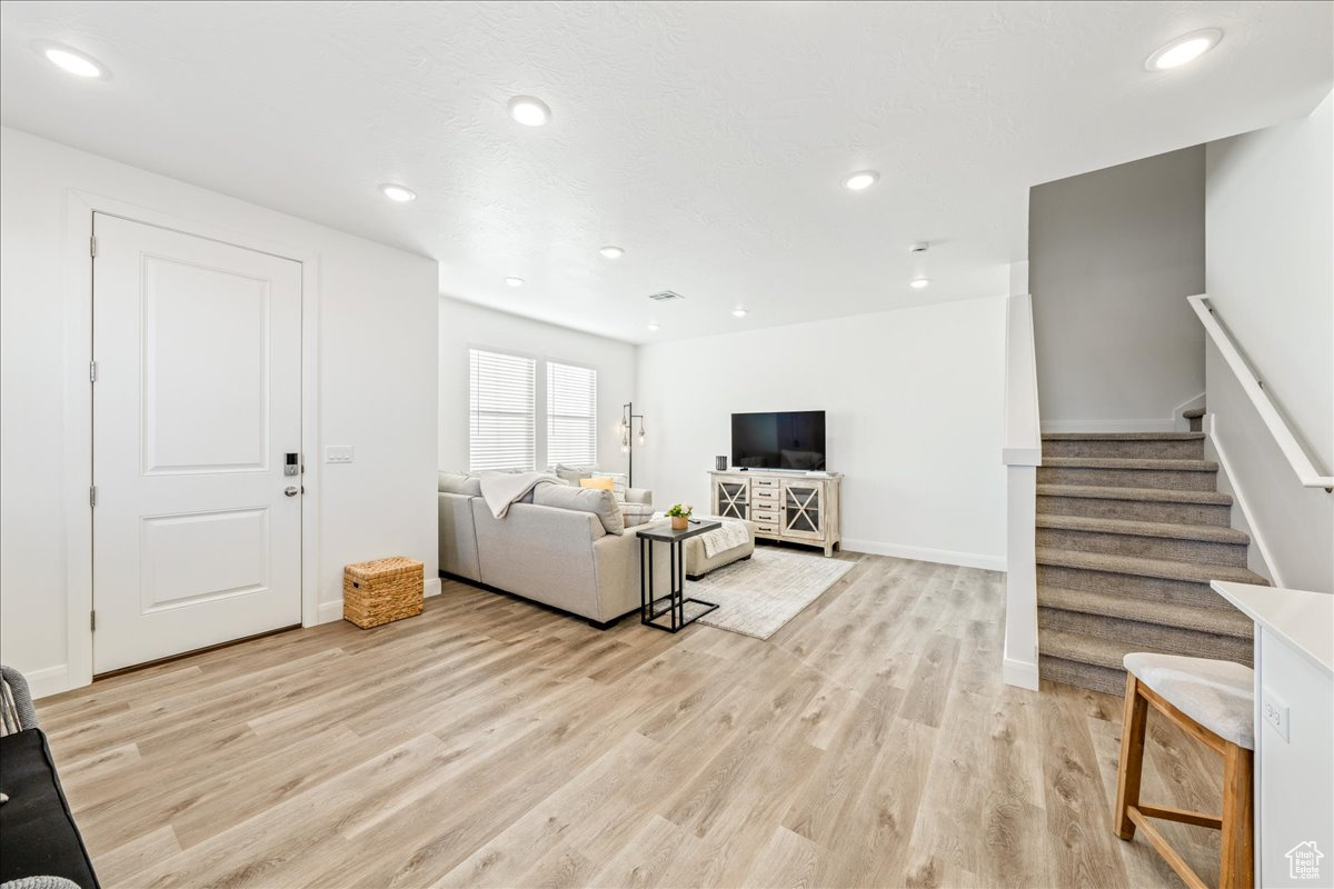 Living area with stairway, recessed lighting, and light wood-type flooring