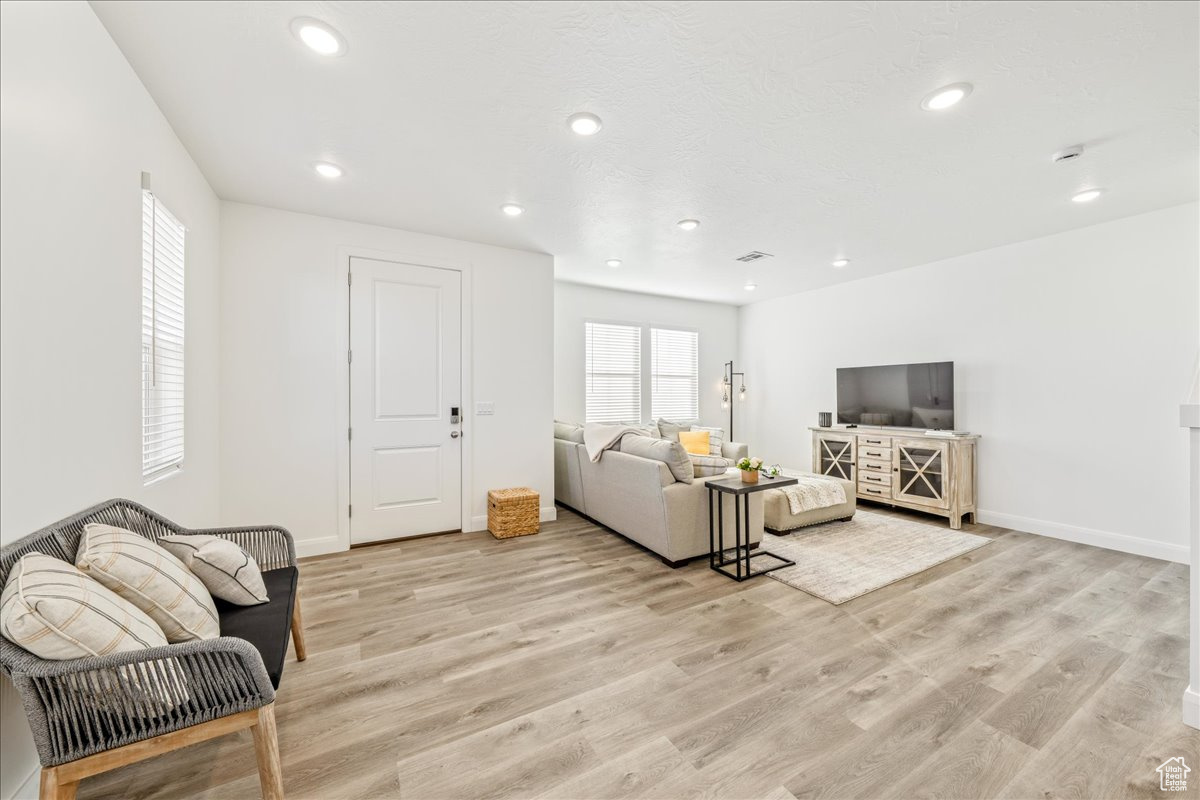 Living room featuring recessed lighting, light wood-style floors, and baseboards