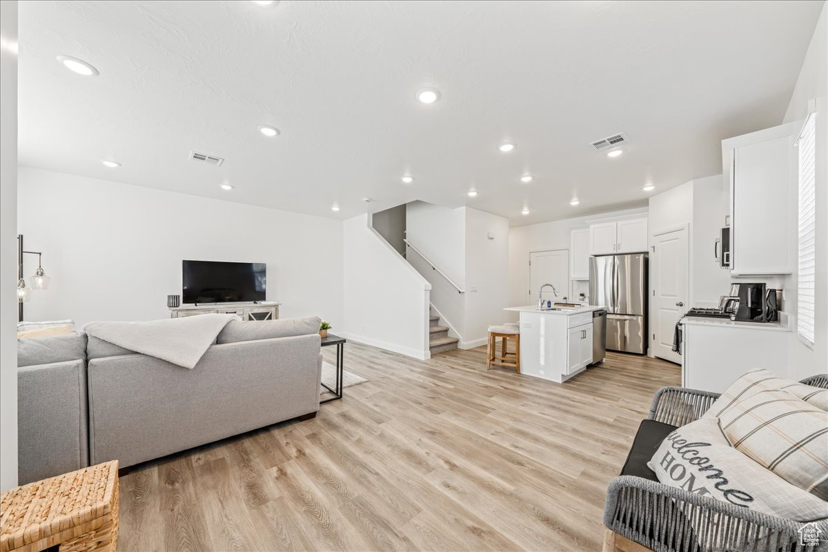 Living room featuring recessed lighting, stairway, light wood-style flooring, and visible vents
