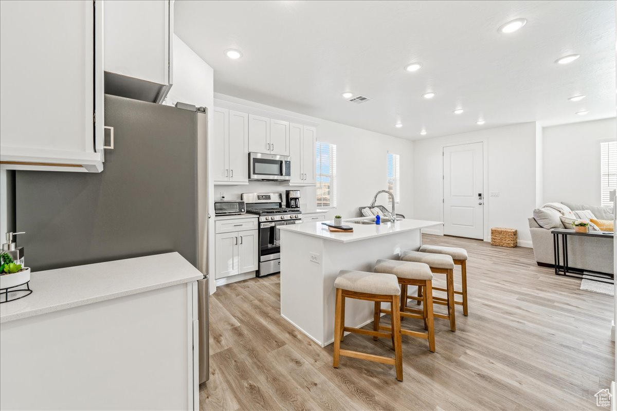 Kitchen with a sink, stainless steel appliances, a kitchen bar, and white cabinets