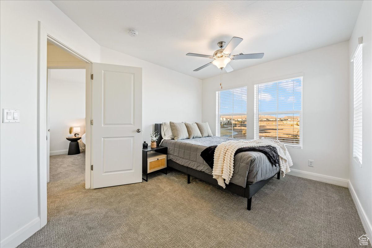Bedroom featuring light colored carpet, a ceiling fan, and baseboards