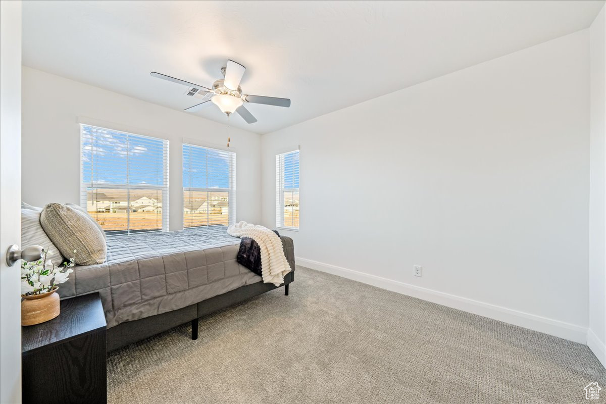Carpeted bedroom with visible vents, baseboards, and ceiling fan