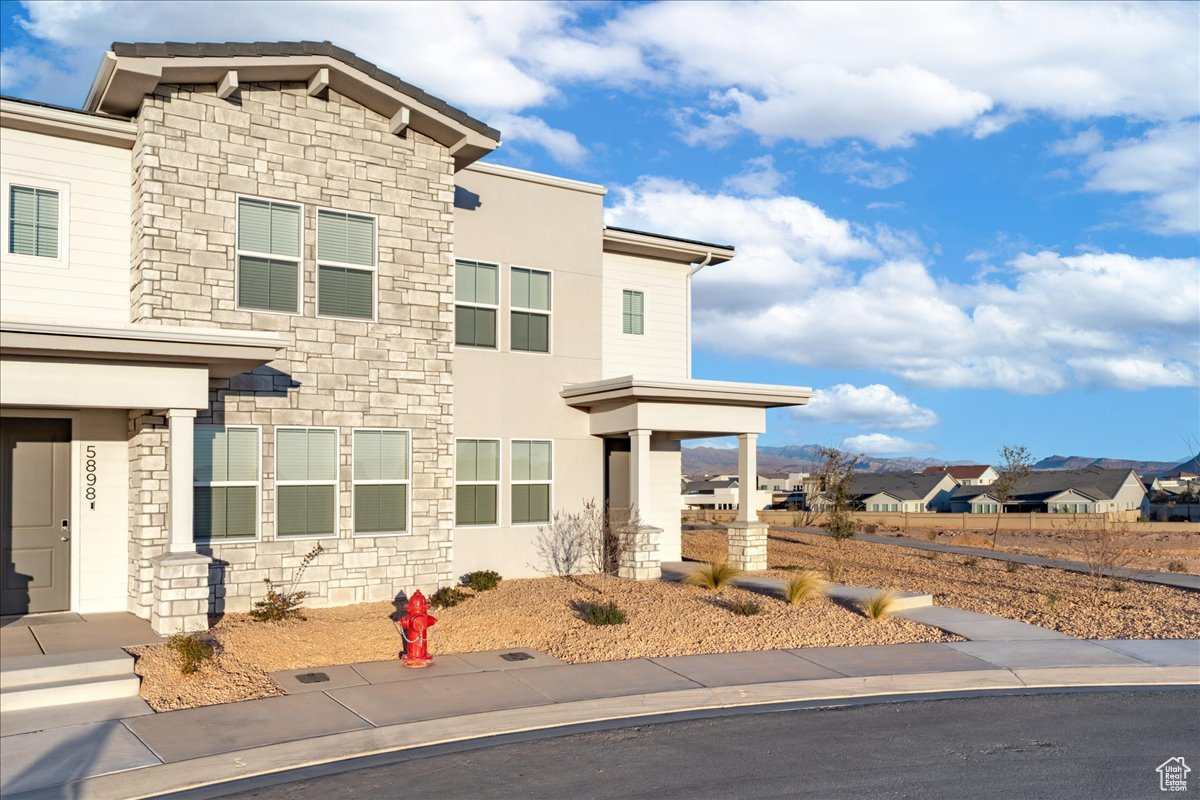 View of front of home featuring stone siding, stucco siding, and a residential view