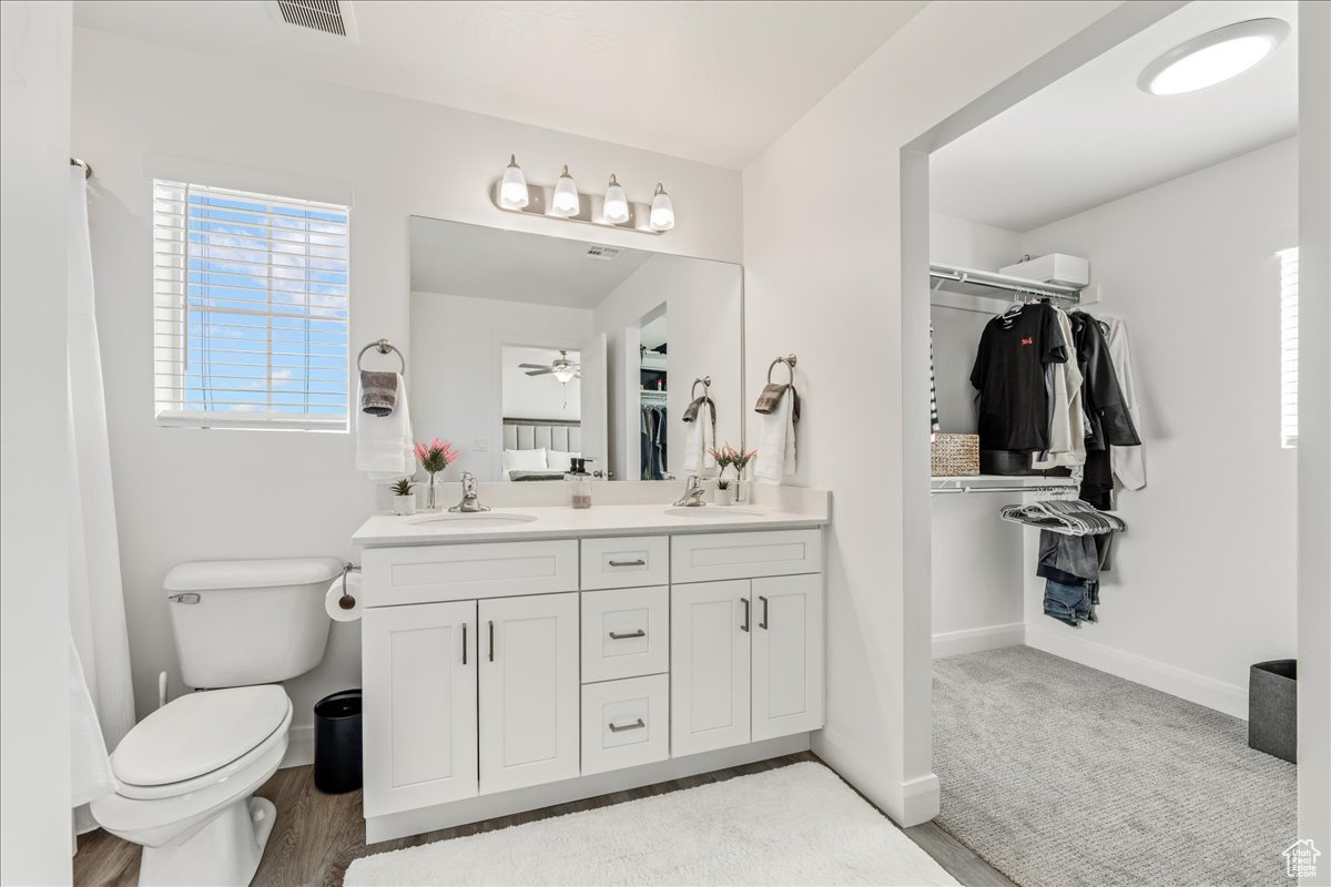 Bathroom featuring a spacious closet, visible vents, baseboards, toilet, and vanity