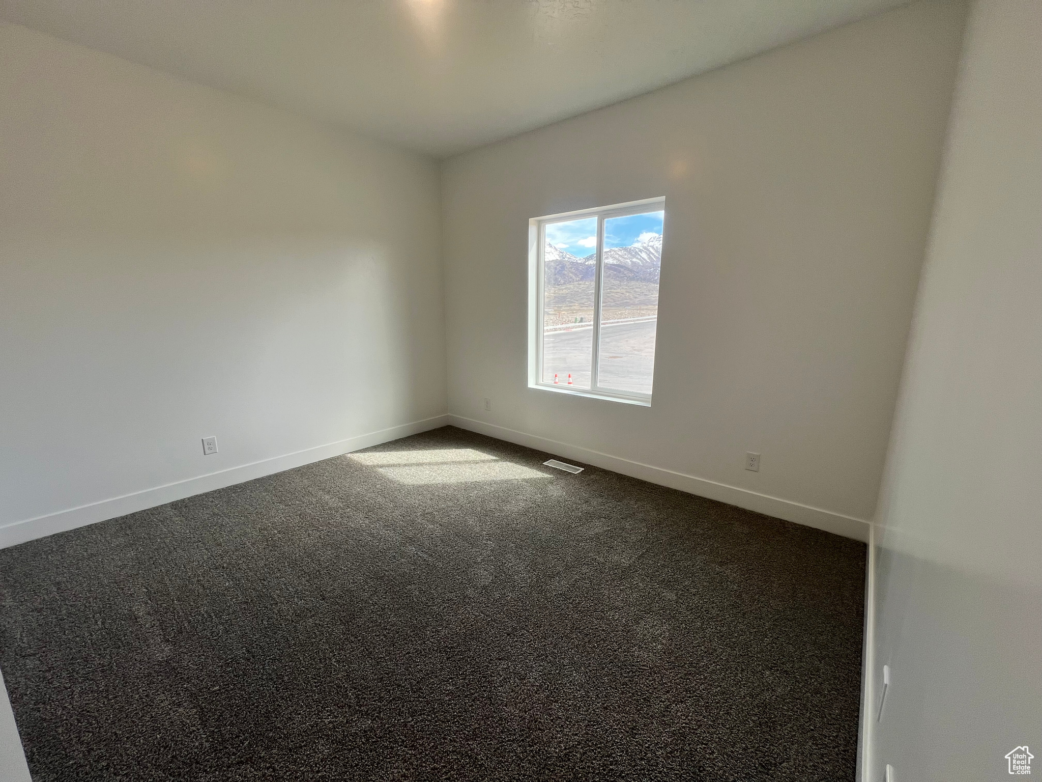Spare room with dark colored carpet, visible vents, and baseboards