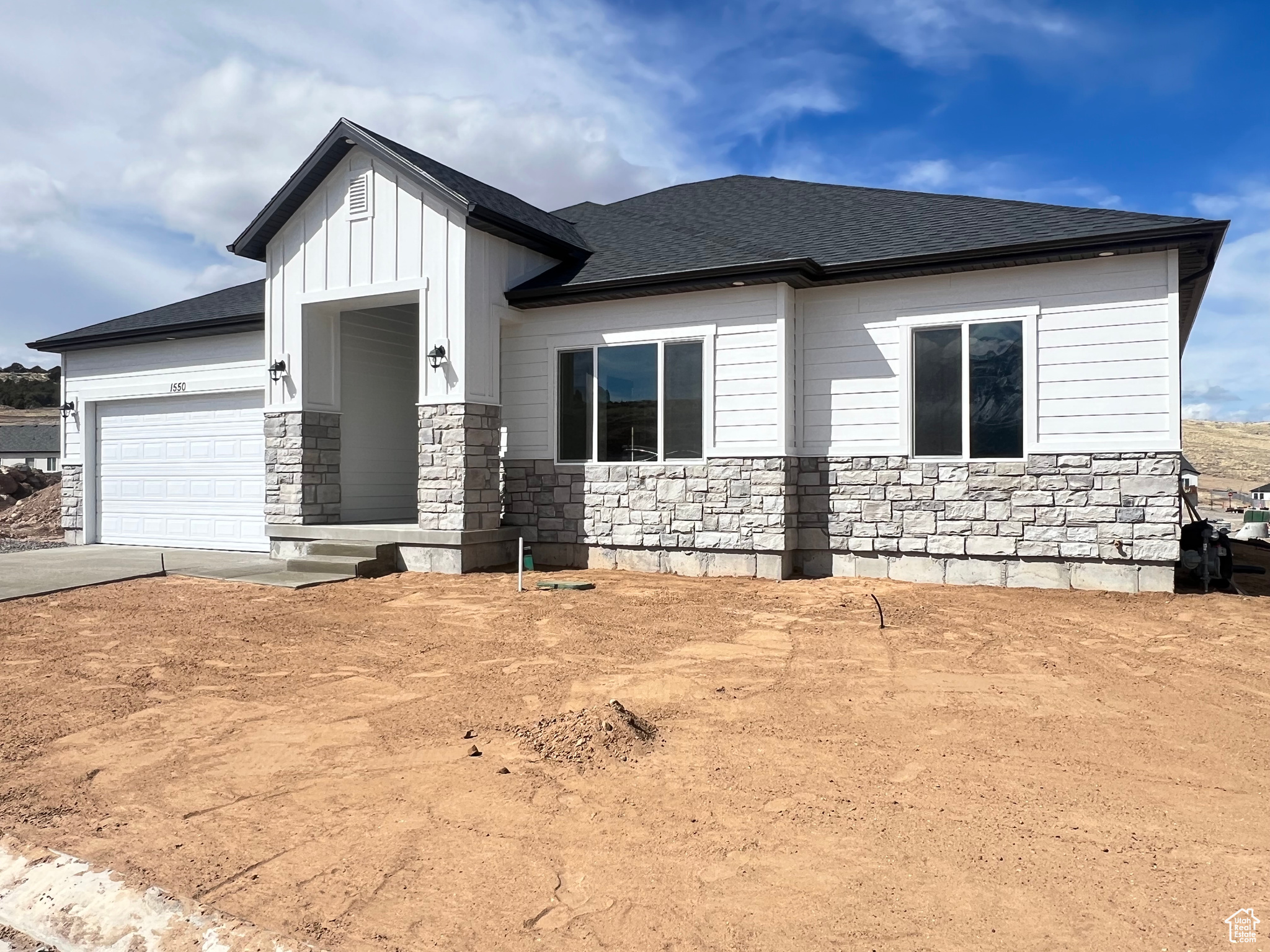 View of front facade with driveway, stone siding, roof with shingles, board and batten siding, and a garage