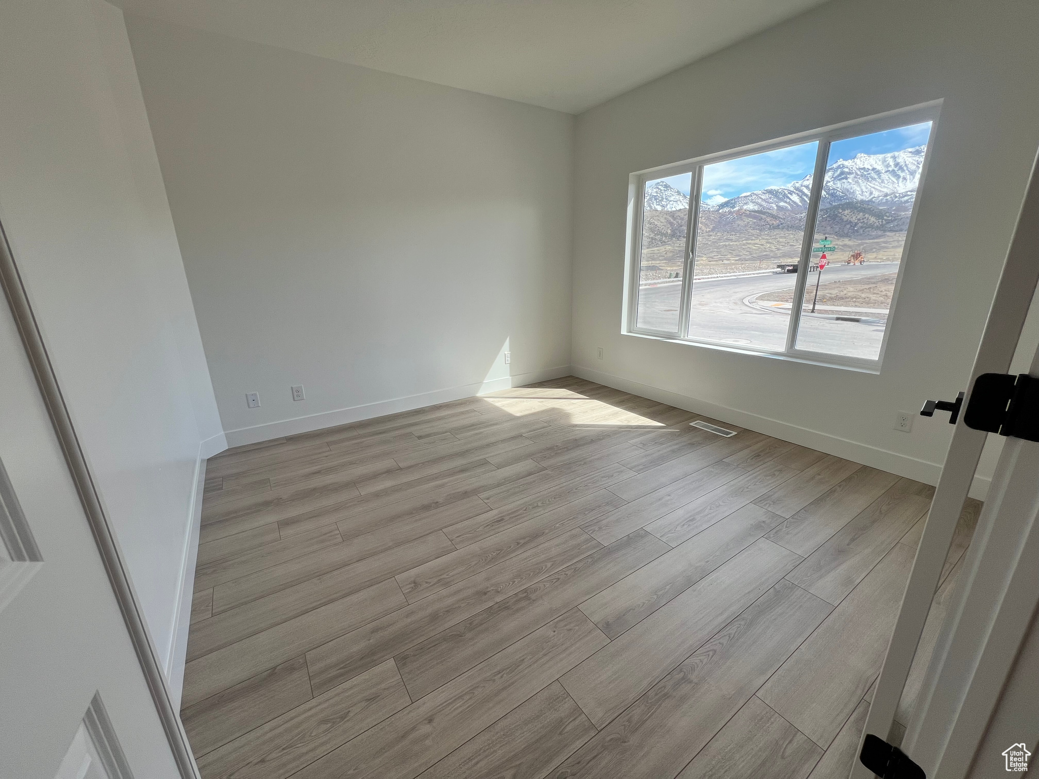 Spare room featuring visible vents, baseboards, and light wood-type flooring