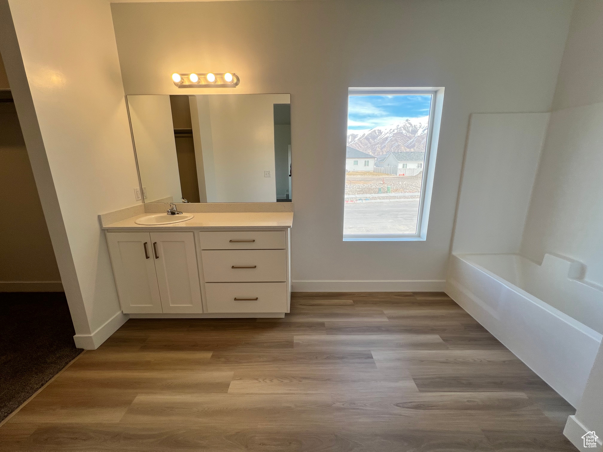 Full bathroom featuring vanity, baseboards, and wood finished floors