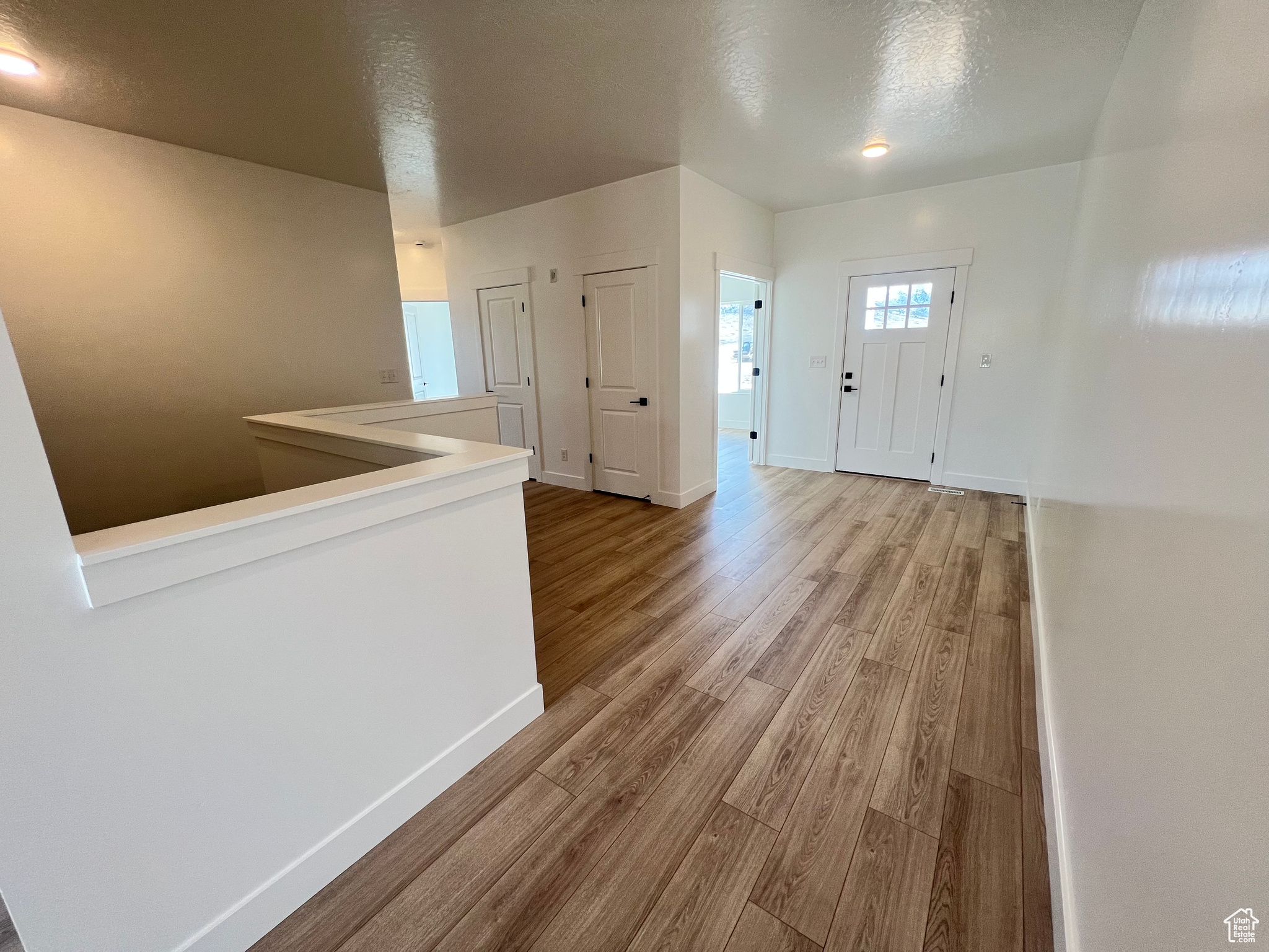 Foyer with baseboards, a textured ceiling, and wood finished floors