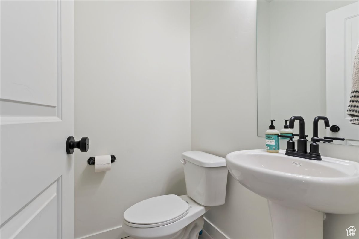 Bathroom with toilet, baseboards, and a sink