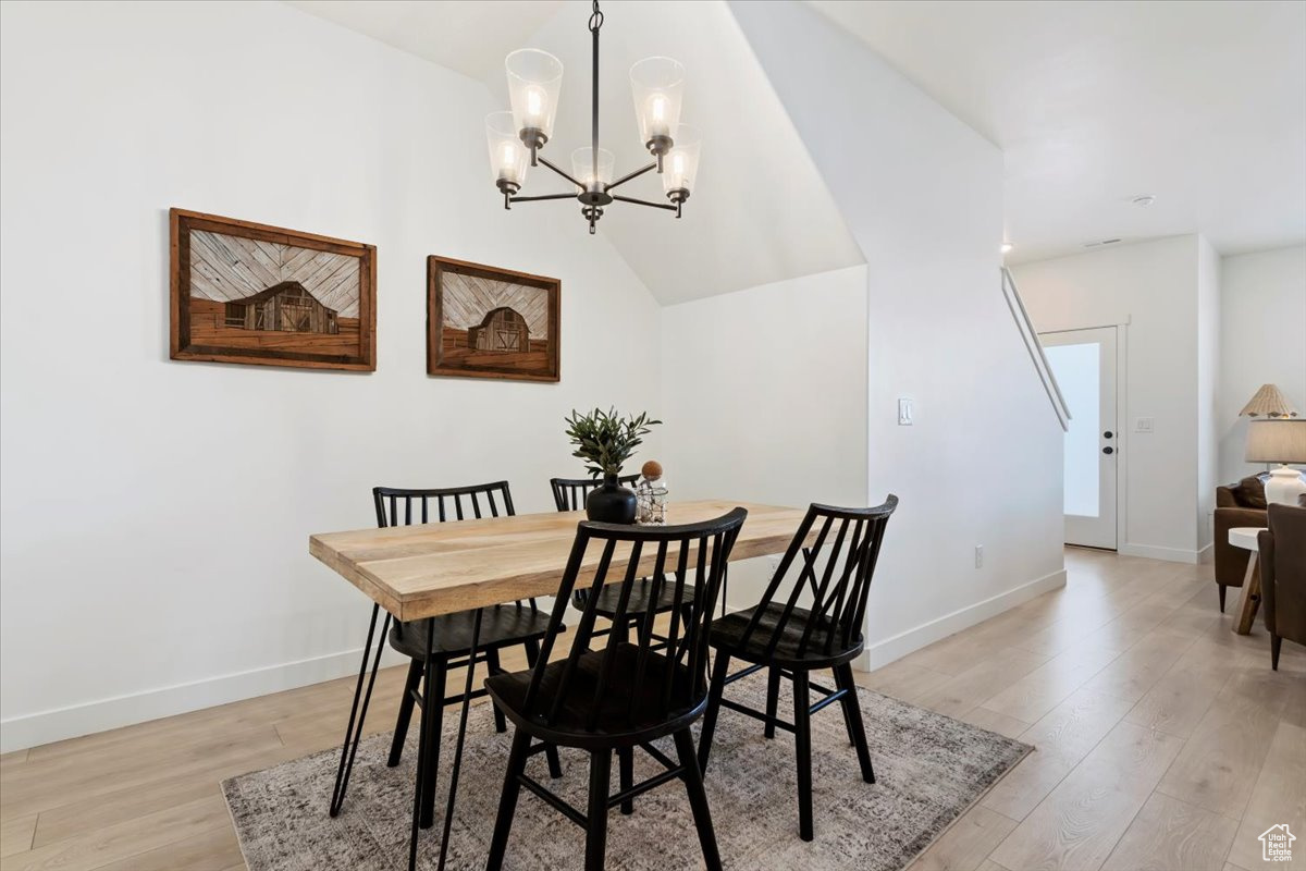 Dining area featuring light wood-type flooring, baseboards, and a notable chandelier