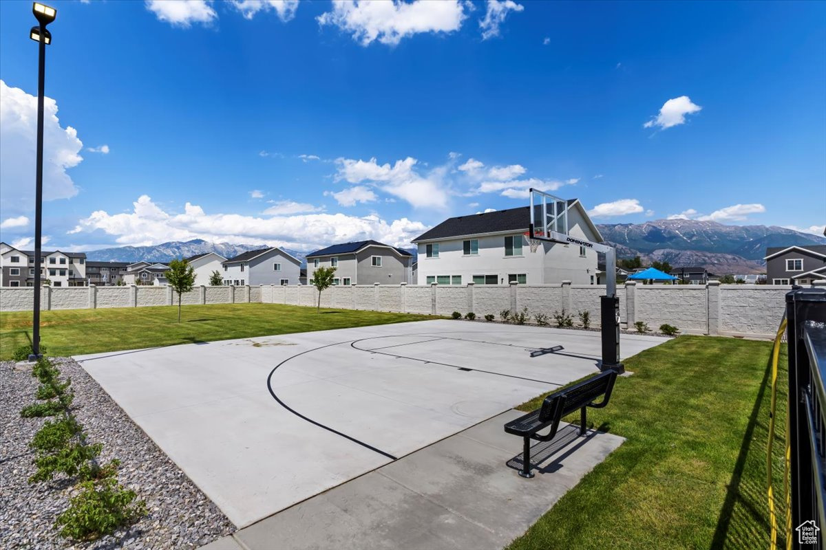View of sport court featuring community basketball court, a fenced backyard, a yard, a residential view, and a mountain view