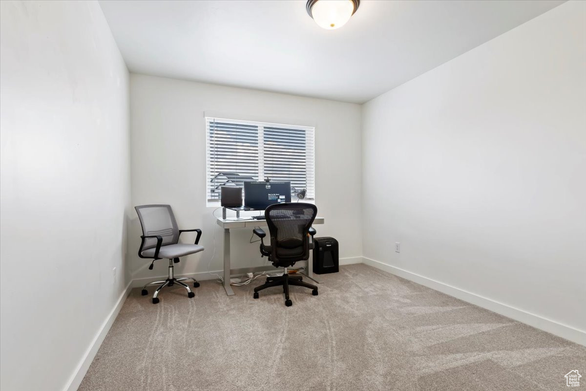 Carpeted home office featuring baseboards