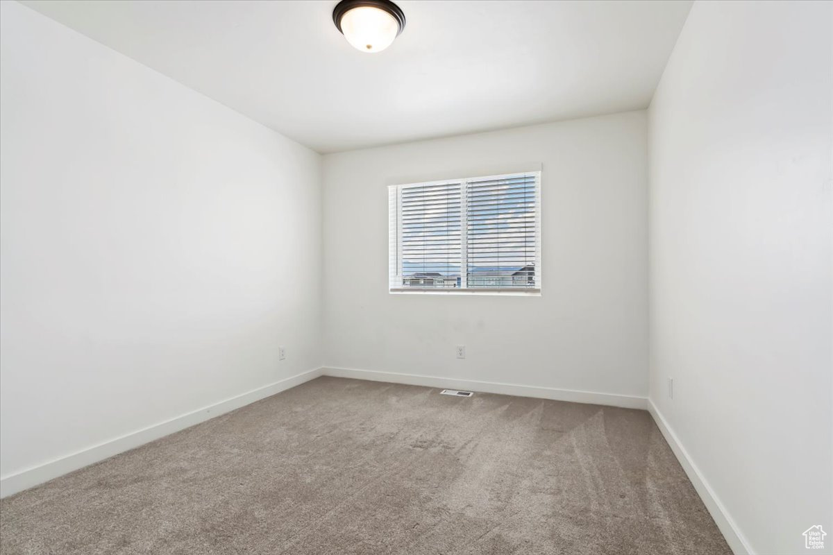 Carpeted spare room featuring visible vents and baseboards