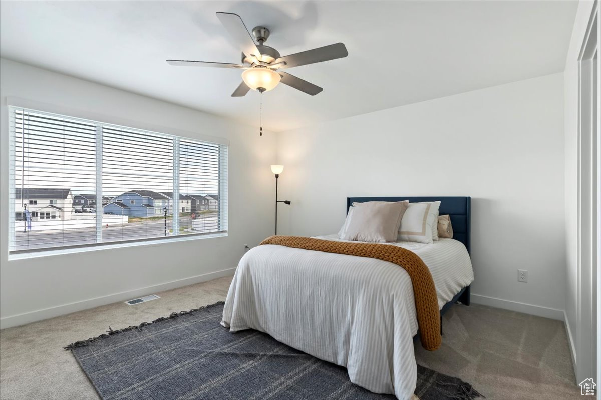 Bedroom featuring a ceiling fan, visible vents, baseboards, and dark colored carpet