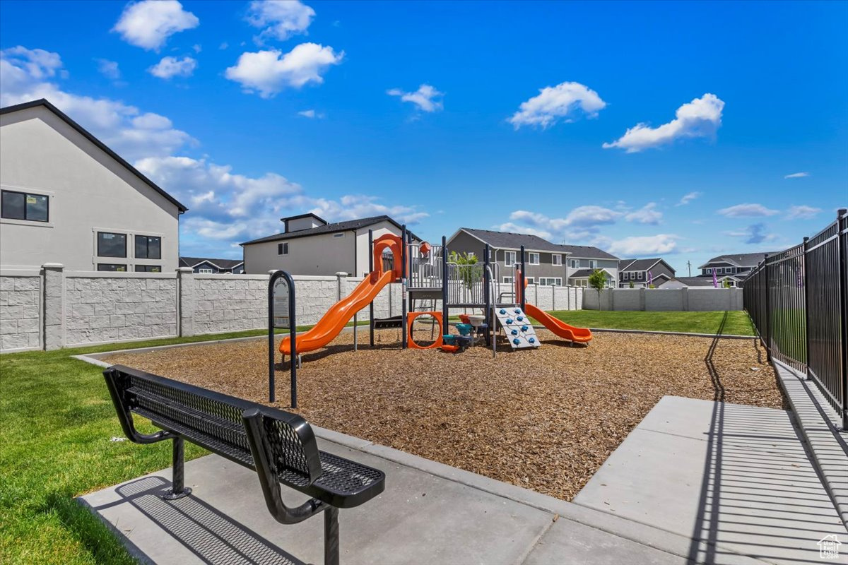 Community jungle gym featuring a residential view, a lawn, and a fenced backyard