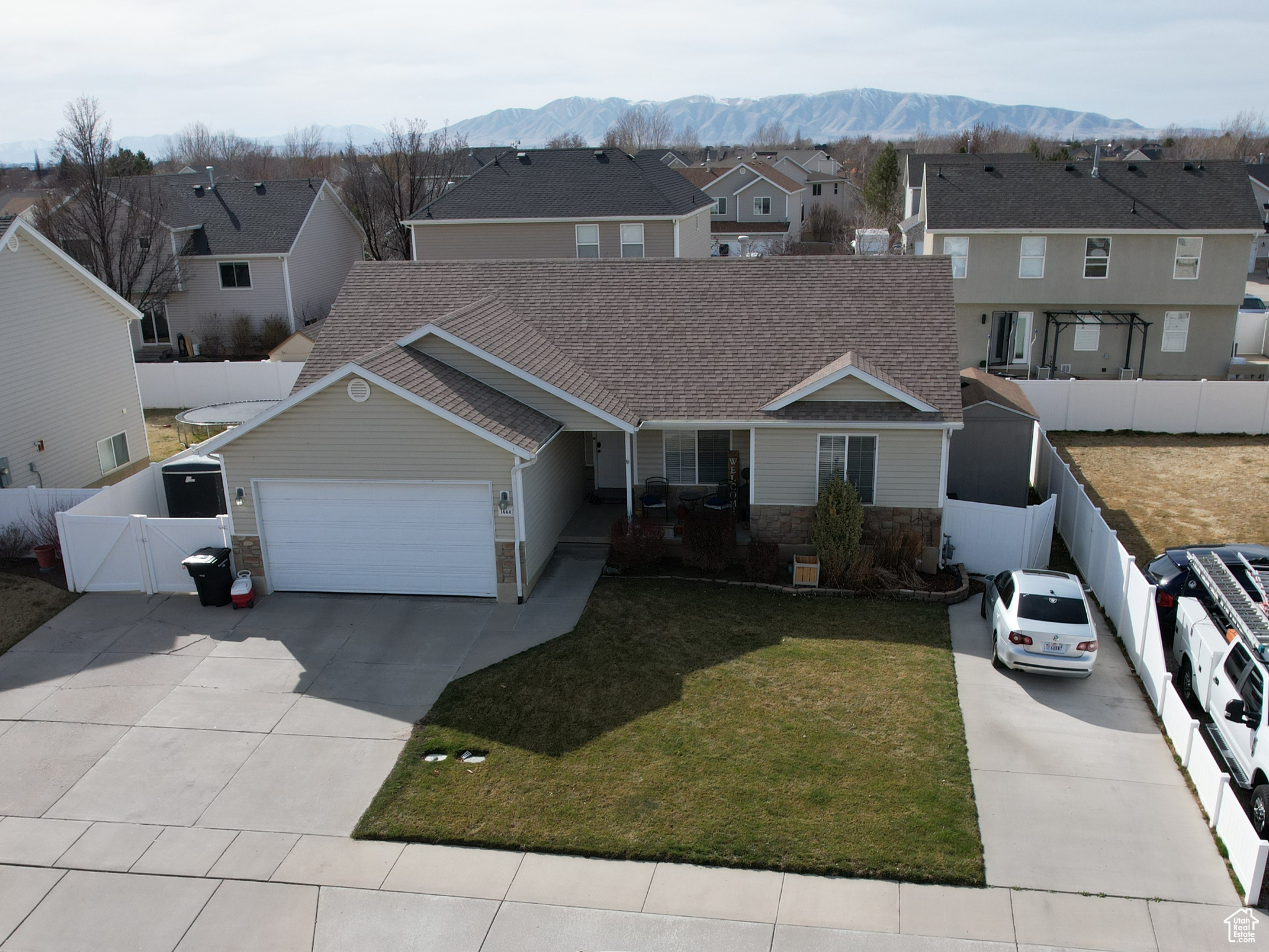 Traditional home featuring an attached garage, fence, a residential view, concrete driveway, and a mountain view