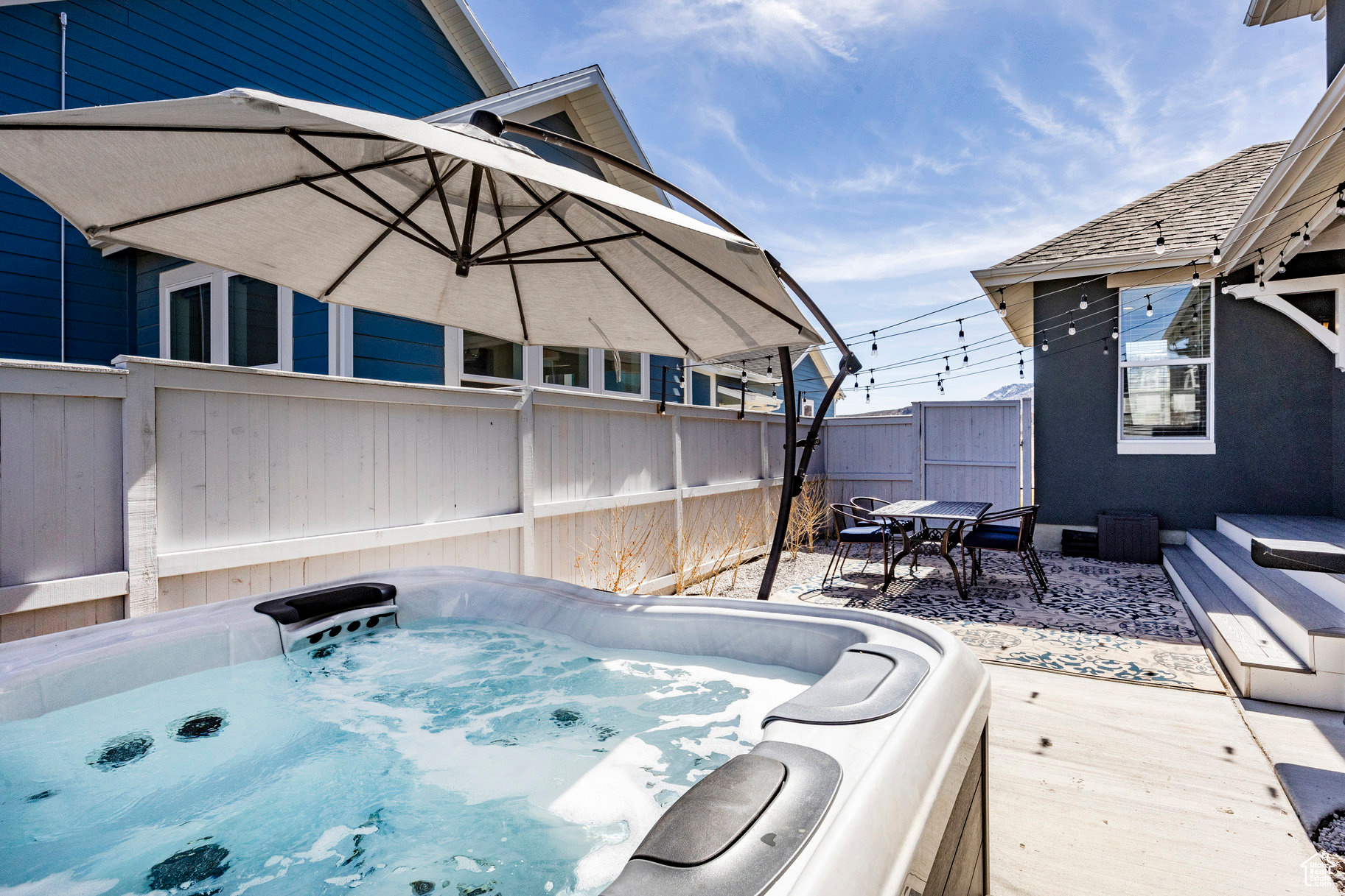 View of patio with fence and a hot tub