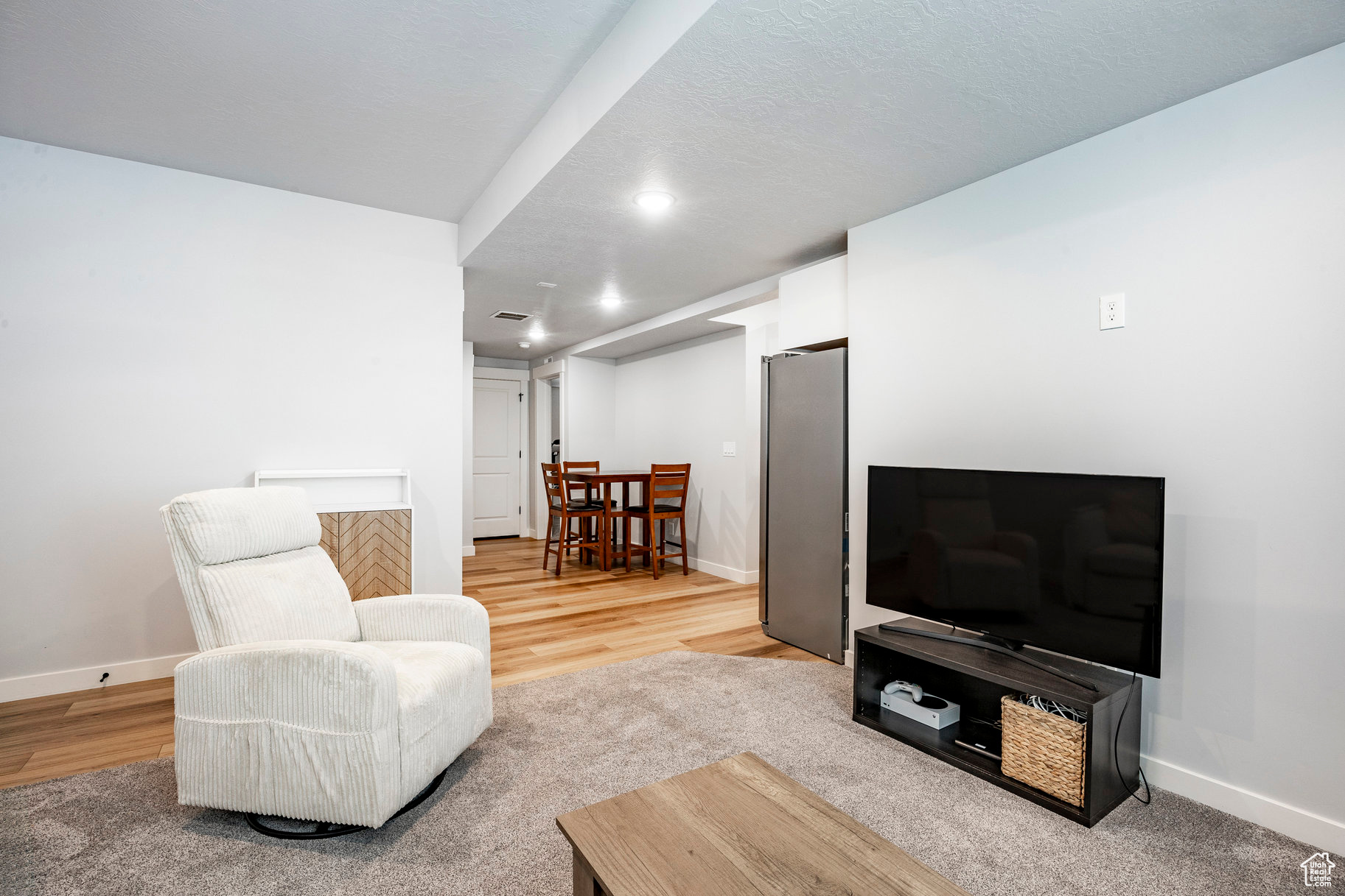 Living area featuring recessed lighting, baseboards, a textured ceiling, and light wood finished floors