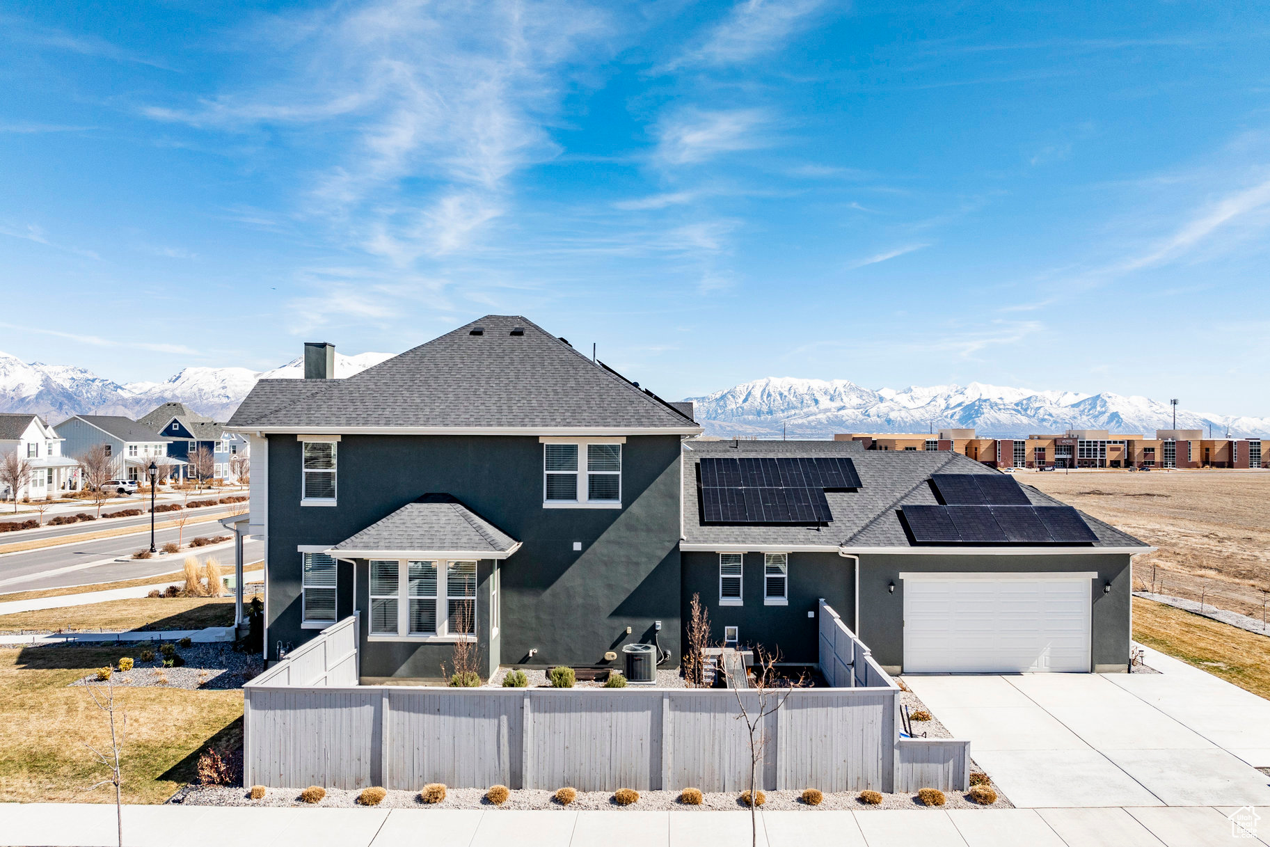 View of front facade featuring solar panels, a mountain view, a fenced front yard, and stucco siding