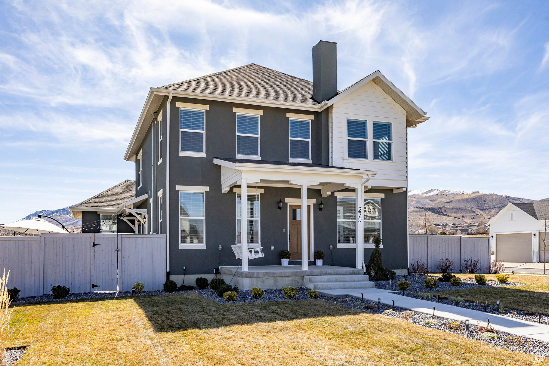 View of front of home with a gate, covered porch, a front yard, and fence