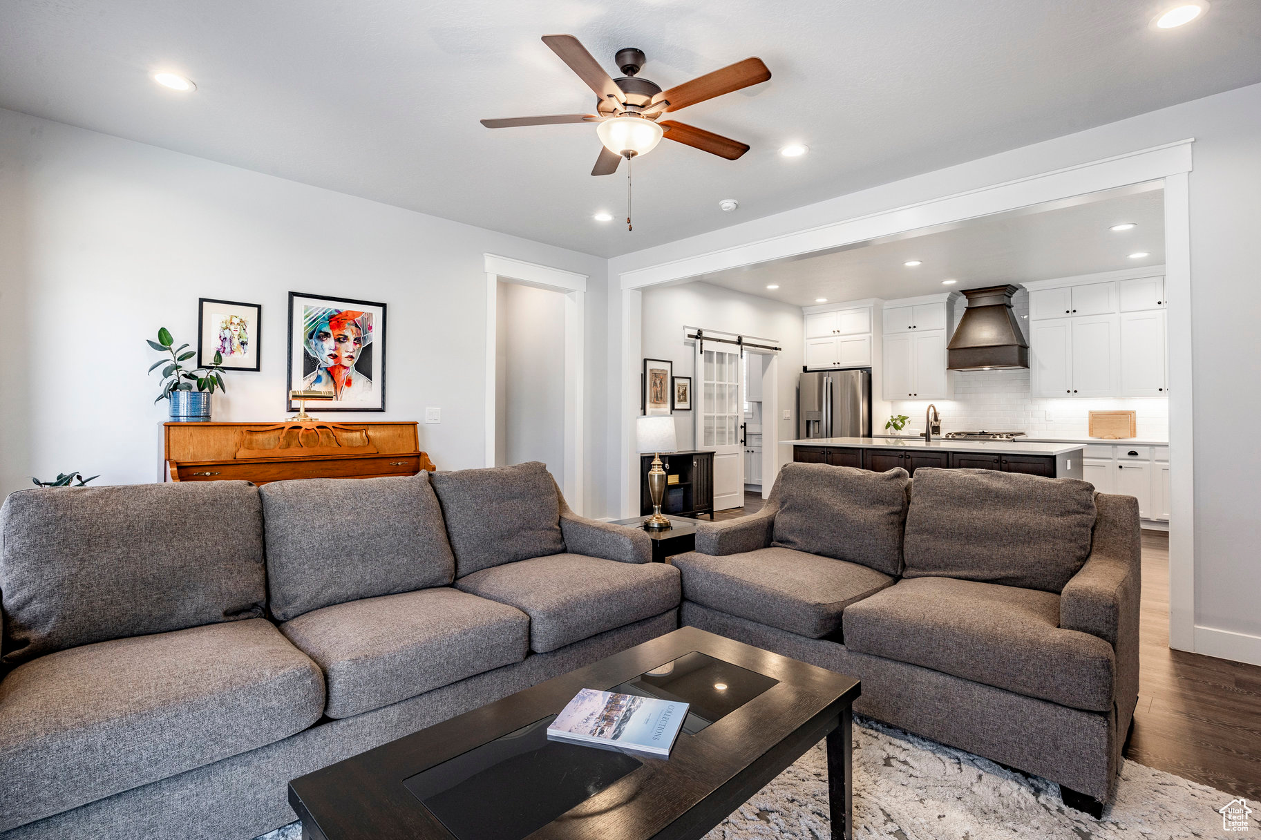 Living room featuring light wood-type flooring, a barn door, ceiling fan, and recessed lighting