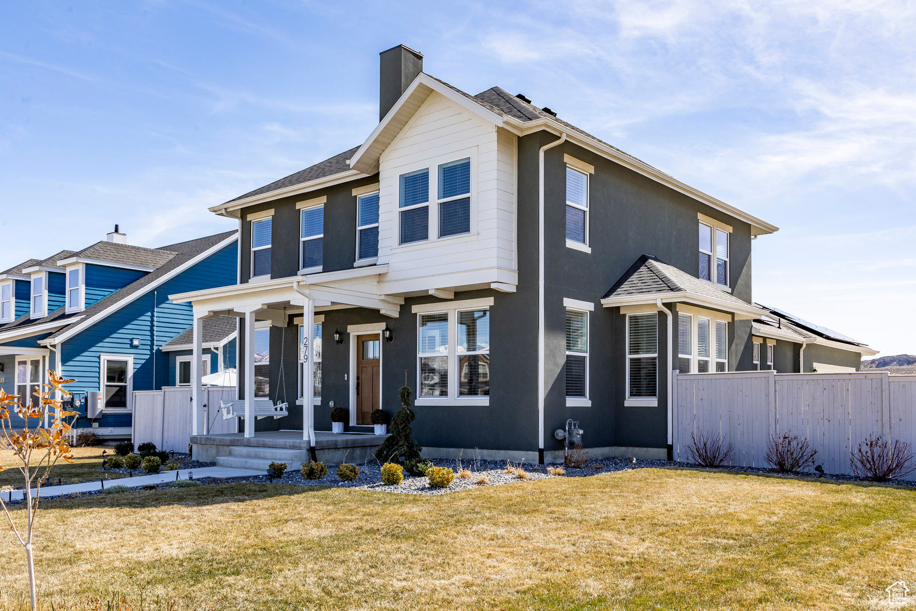 View of front of home with stucco siding, a front lawn, fence, covered porch, and a chimney
