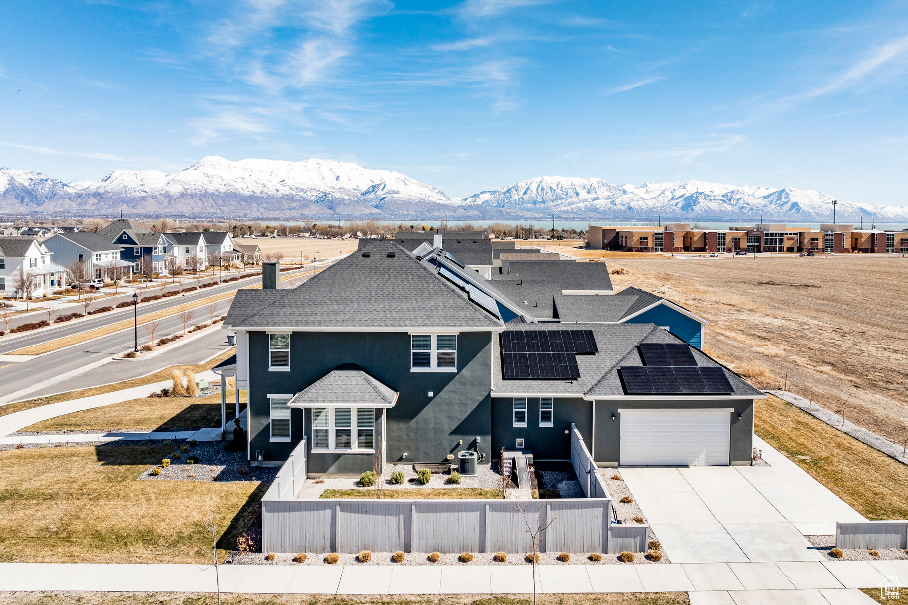 View of front of property featuring solar panels, a fenced front yard, concrete driveway, a garage, and a mountain view