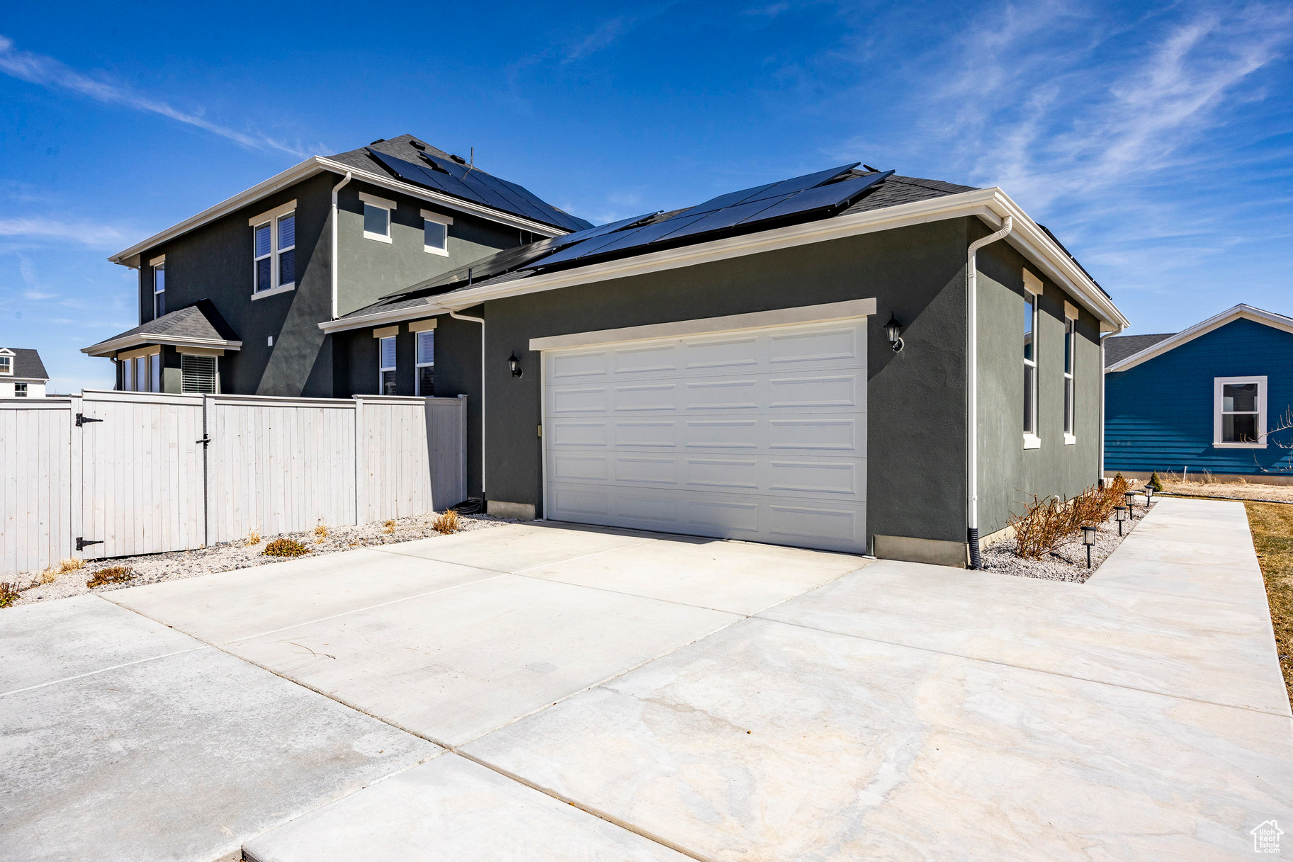 View of property exterior featuring fence, stucco siding, a garage, driveway, and a gate