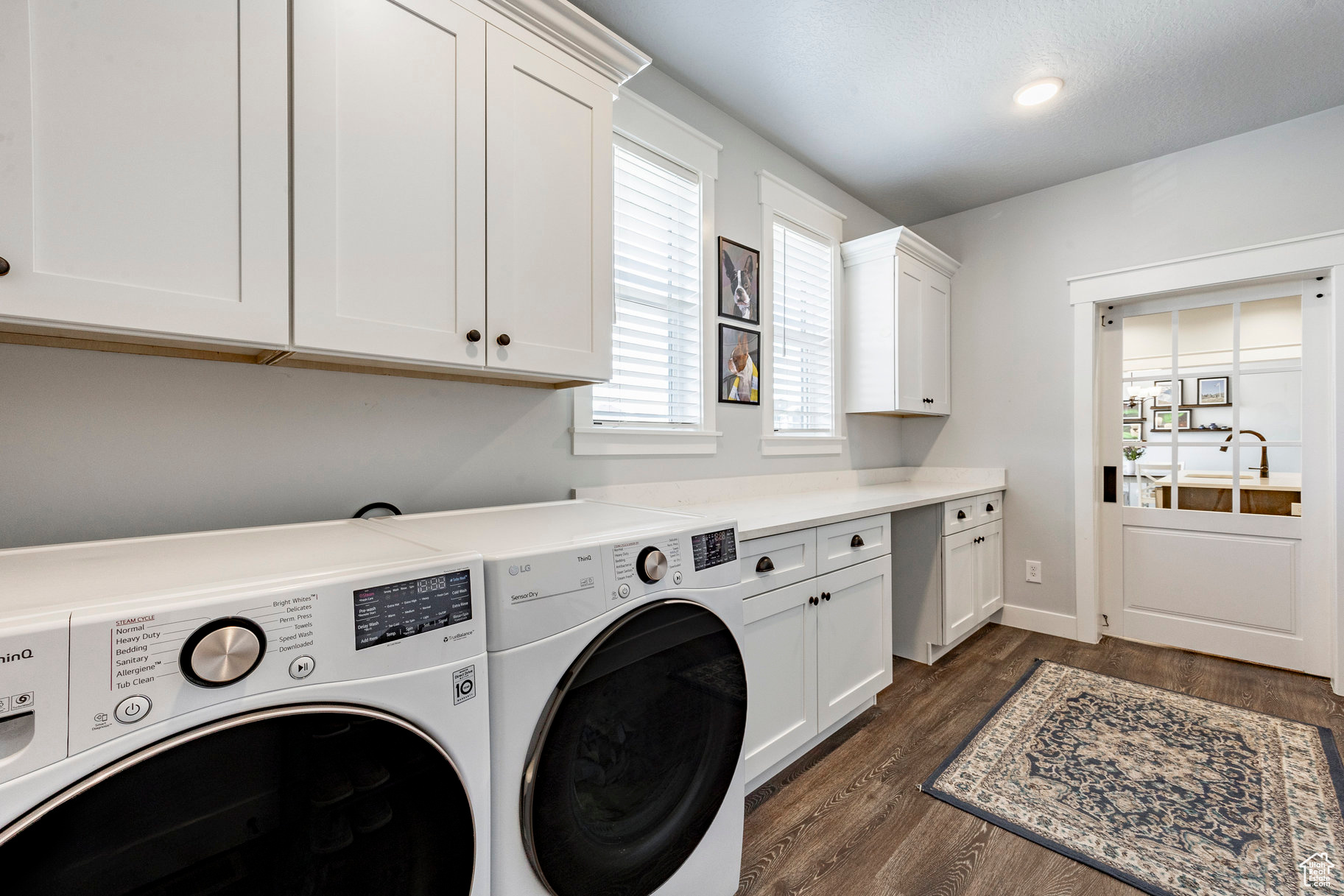 Clothes washing area featuring washer and dryer, baseboards, cabinet space, and dark wood-style flooring