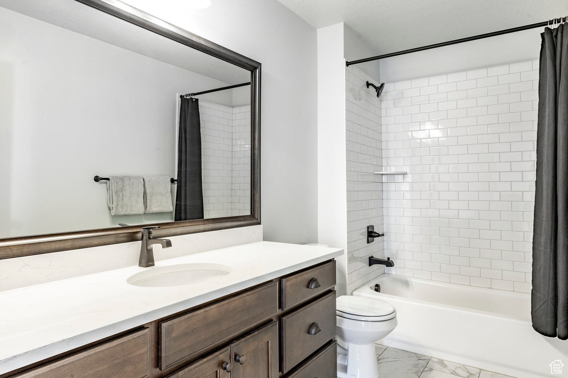 Bathroom featuring vanity, marble finish floor, shower / tub combo, and toilet