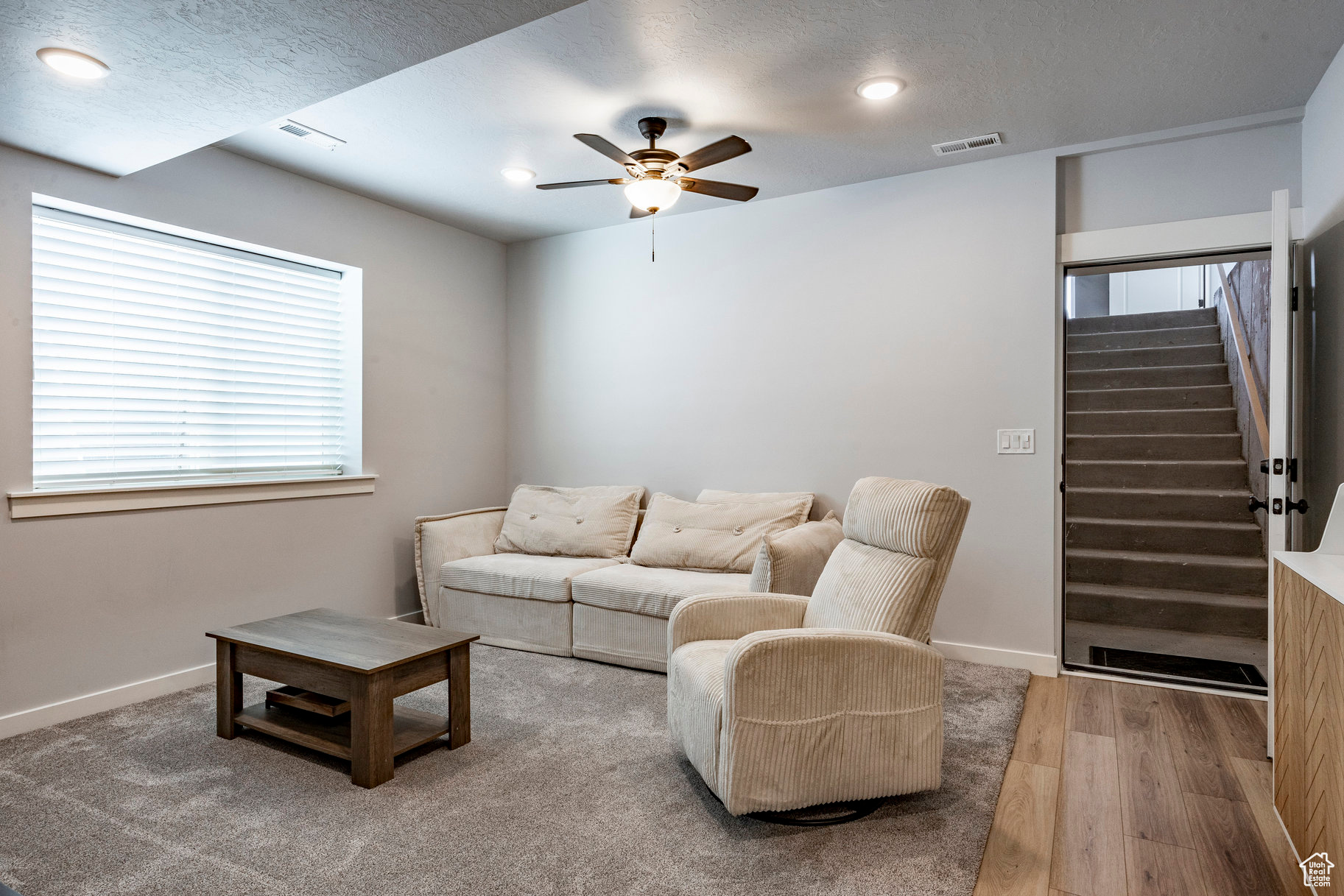 Living area featuring visible vents, stairway, baseboards, and wood finished floors
