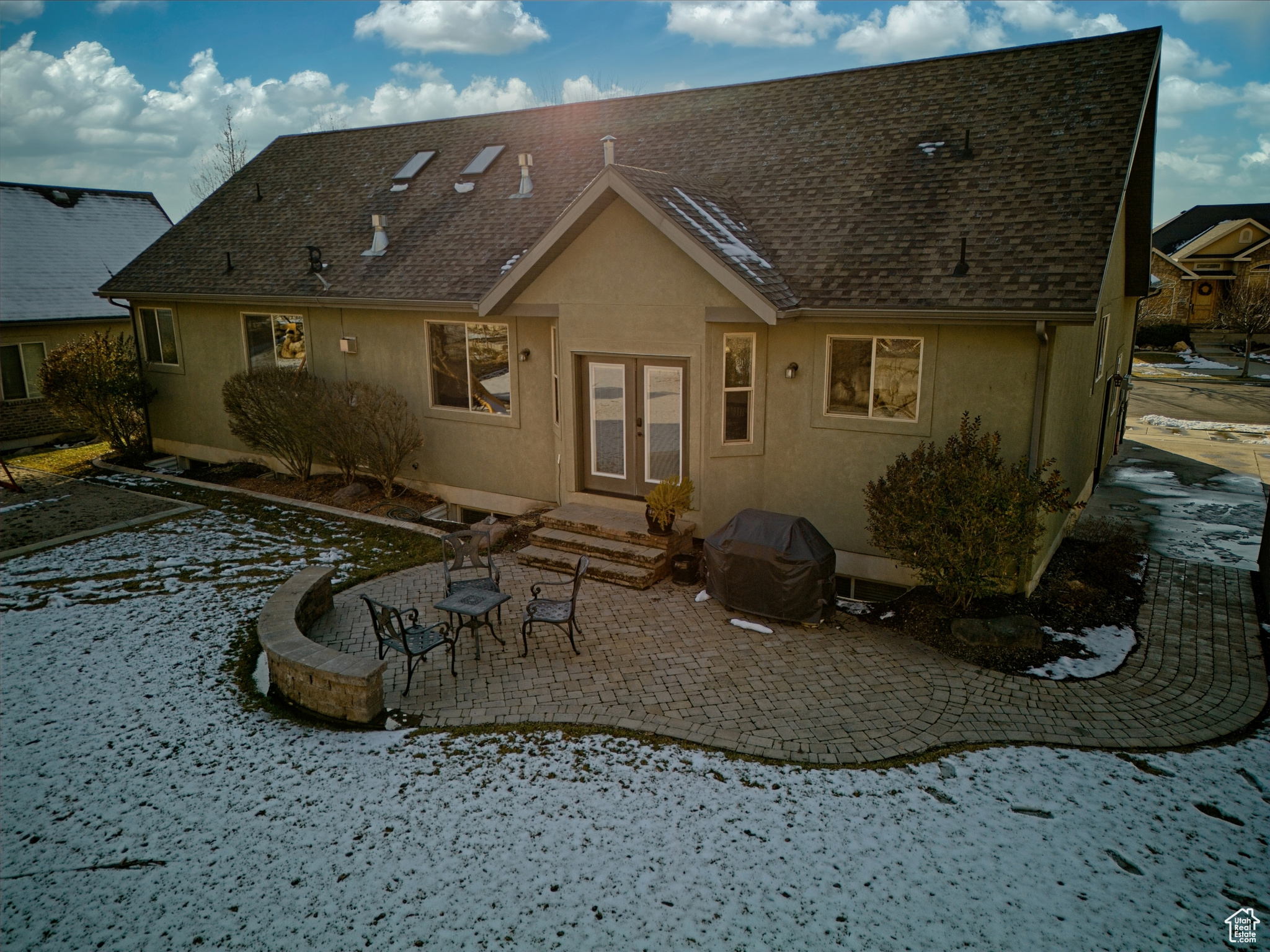 Back of house with a shingled roof, a patio area,  and stucco siding