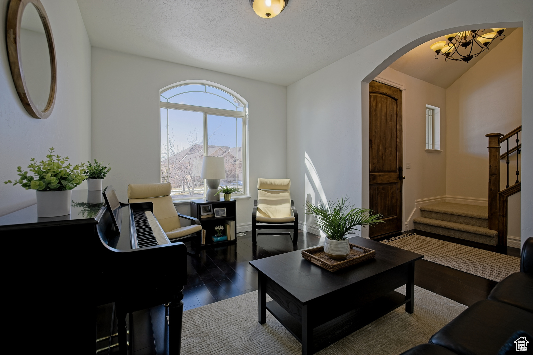 Living room featuring archway, window, wood floors, and chandelier