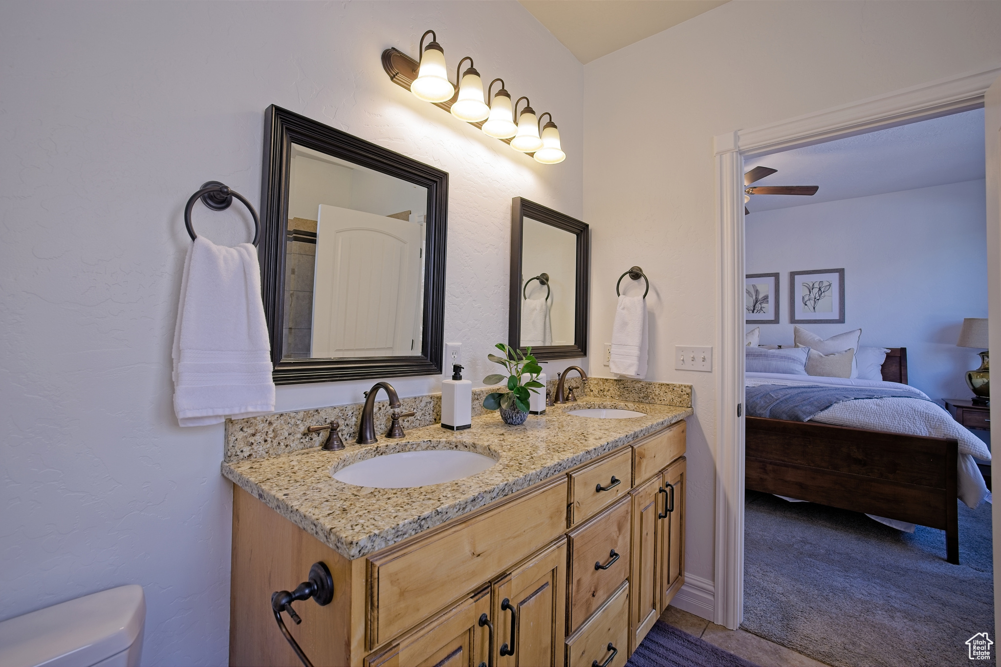 Ensuite bathroom with double vanity, connected bathroom, toilet, and a sink