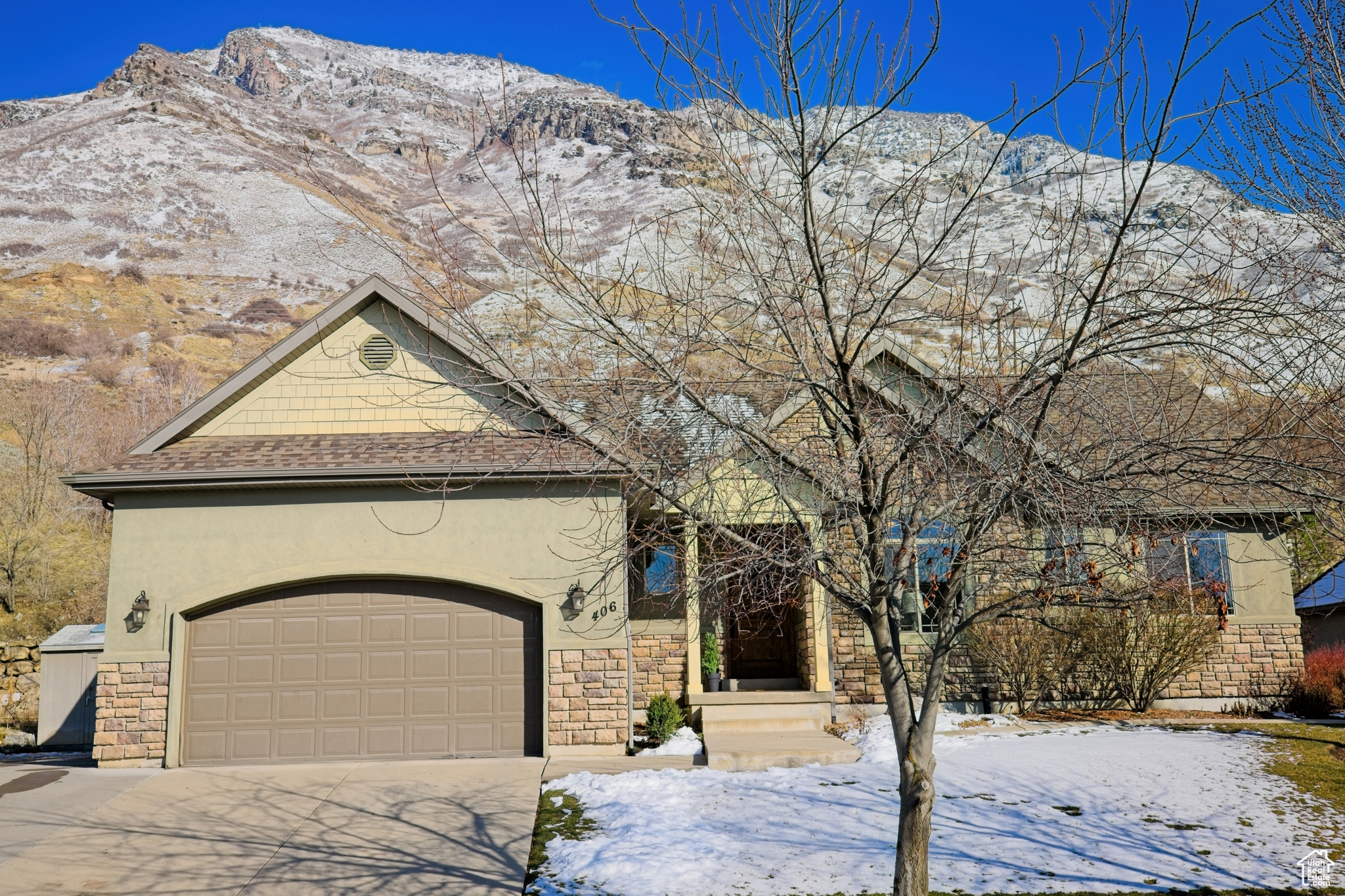 View of front of home featuring concrete driveway, a mountain view, stone siding, and stucco siding