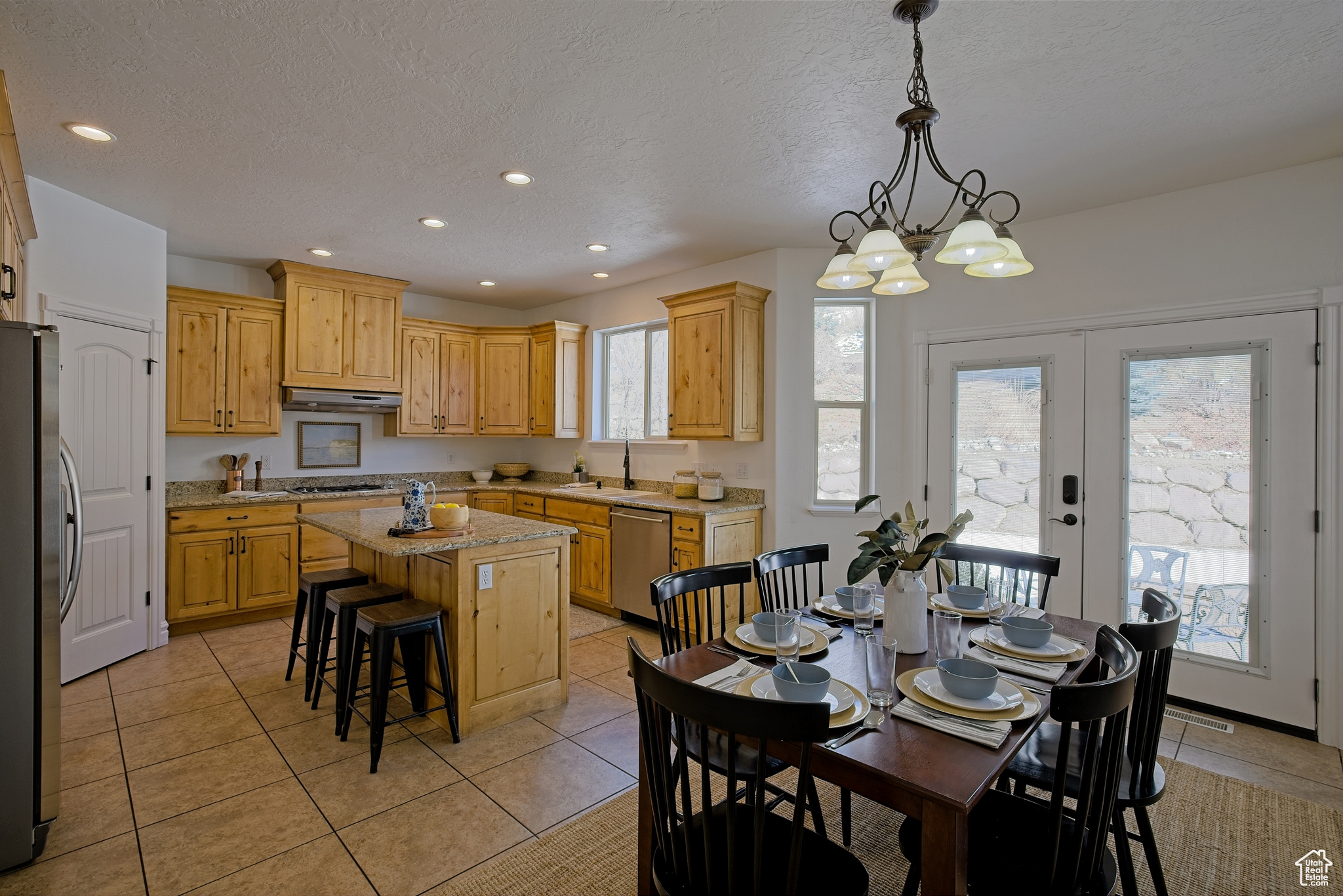 Kitchen with under cabinet range hood, a sink, a kitchen island, and stainless steel appliances