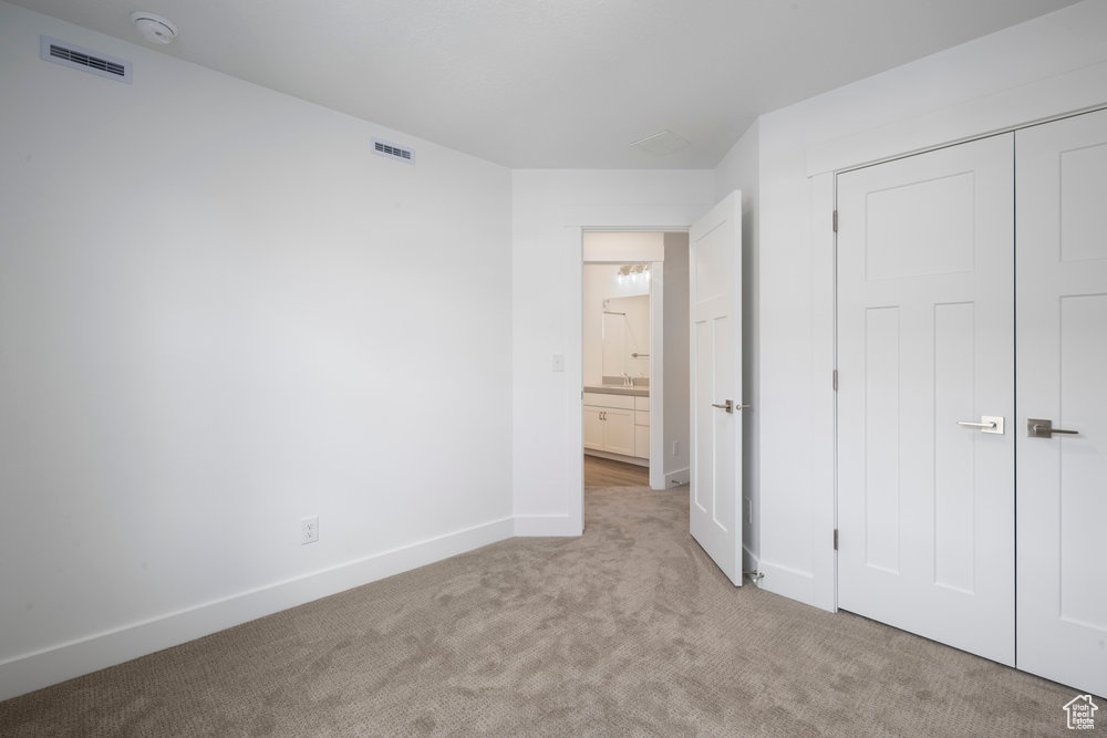 Unfurnished bedroom with light colored carpet, visible vents, a closet, and baseboards