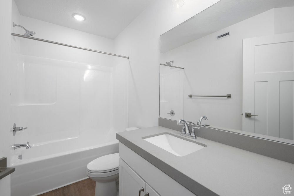 Bathroom with vanity, wood finished floors, visible vents, tub / shower combination, and toilet