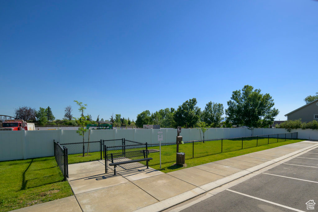 Surrounding community with a gate, a yard, fence, and uncovered parking