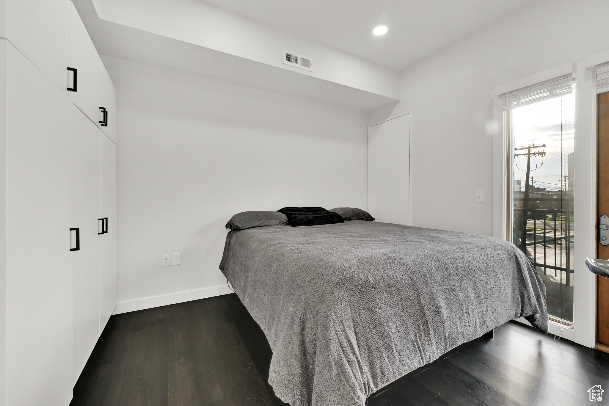 Bedroom featuring visible vents, dark wood-style flooring, baseboards, and access to outside