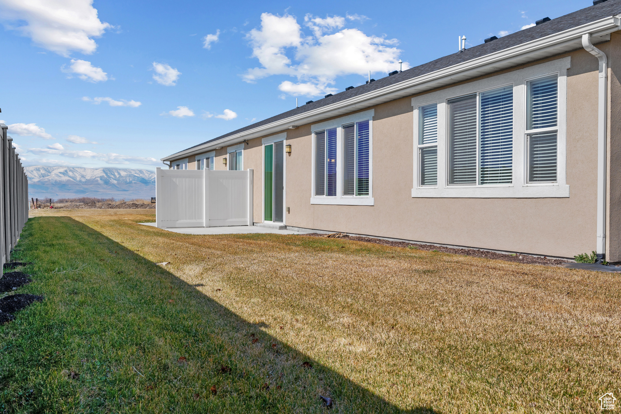 Rear view of house featuring a lawn, a mountain view, and stucco siding