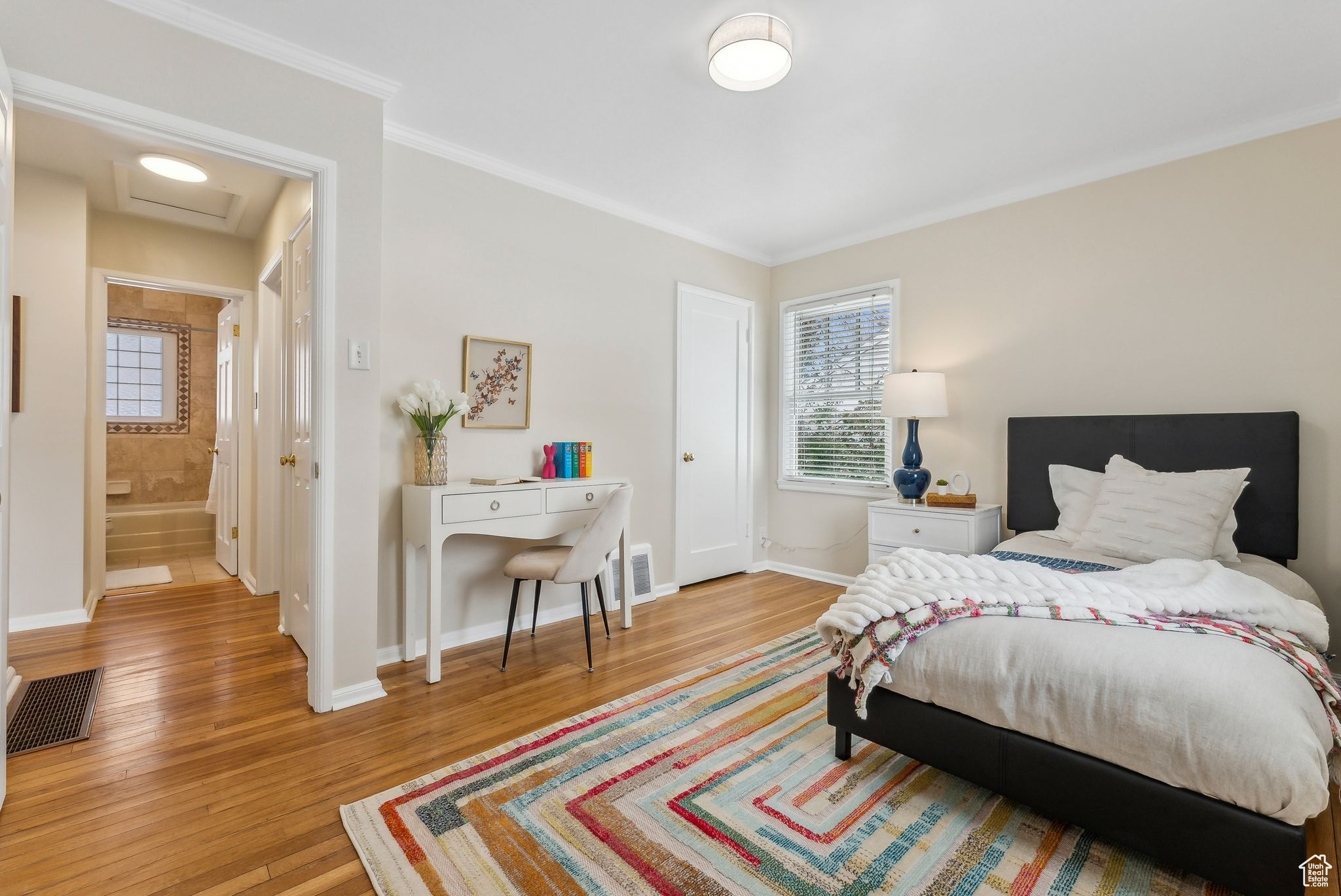 Bedroom featuring attic access, crown molding, wood finished floors, and baseboards