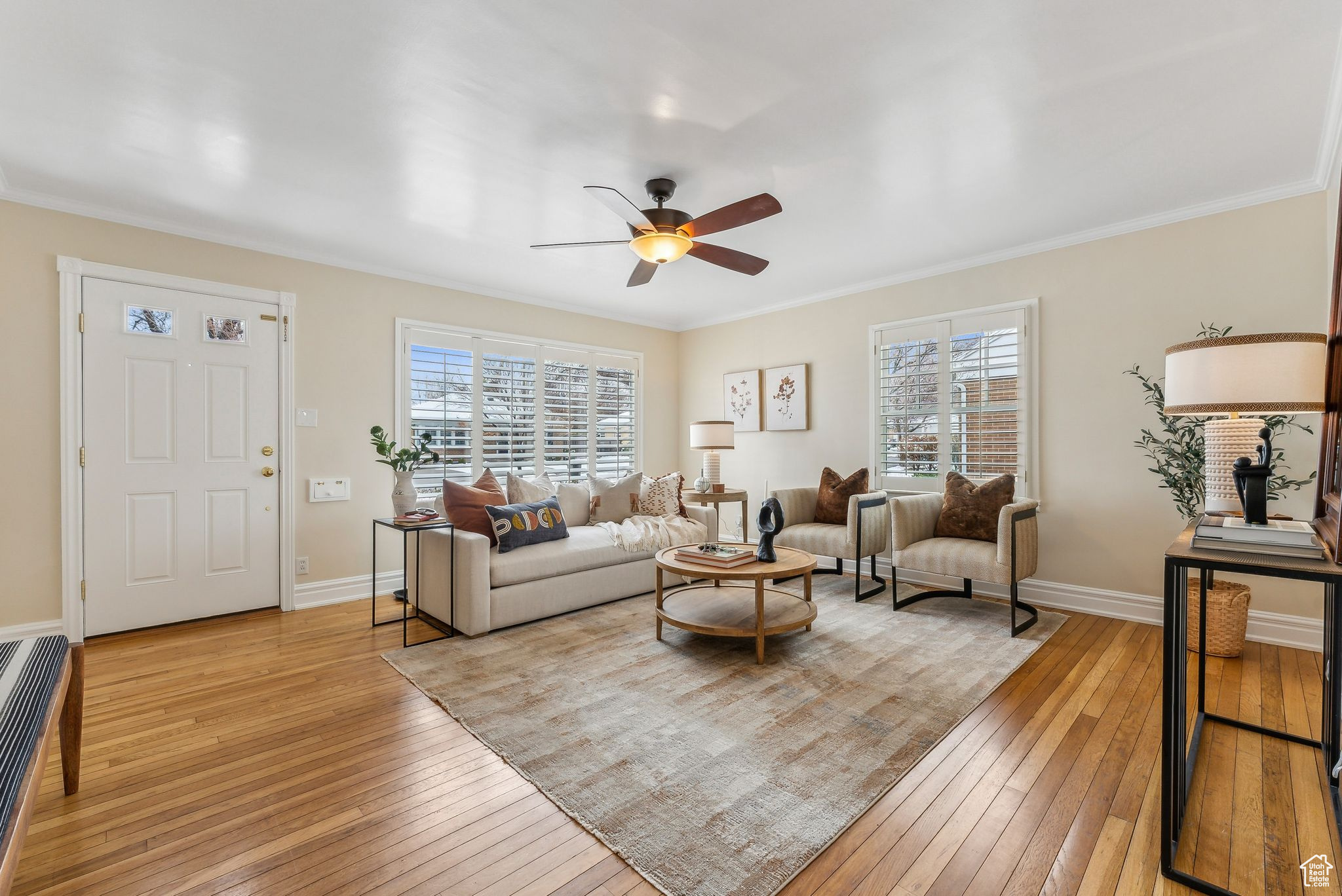 Living area with light wood-style flooring, a ceiling fan, baseboards, and ornamental molding